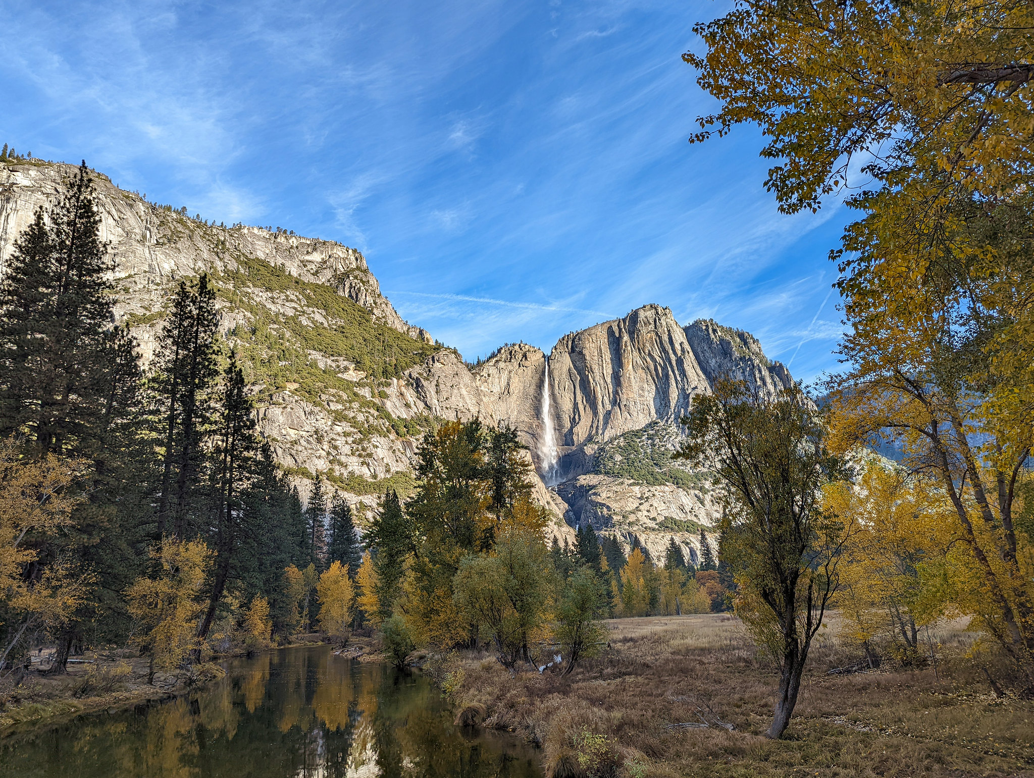 A river set among towering peaks with trees scattered around