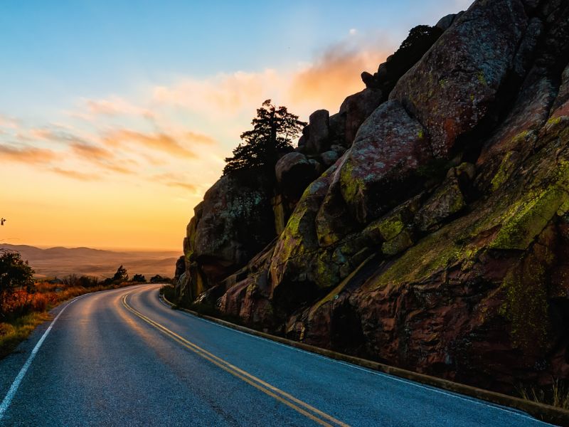 road alongside mountain with sun setting in back