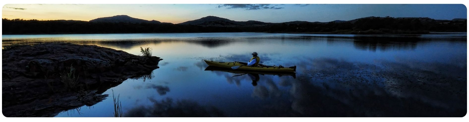 Kayaker in water, looking at mountains in distance